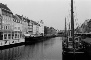 Monochrome photo of Copenhagen harbor with boats and classic architecture along the canal.