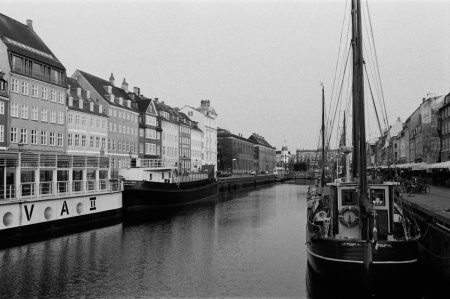 Monochrome photo of Copenhagen harbor with boats and classic architecture along the canal.