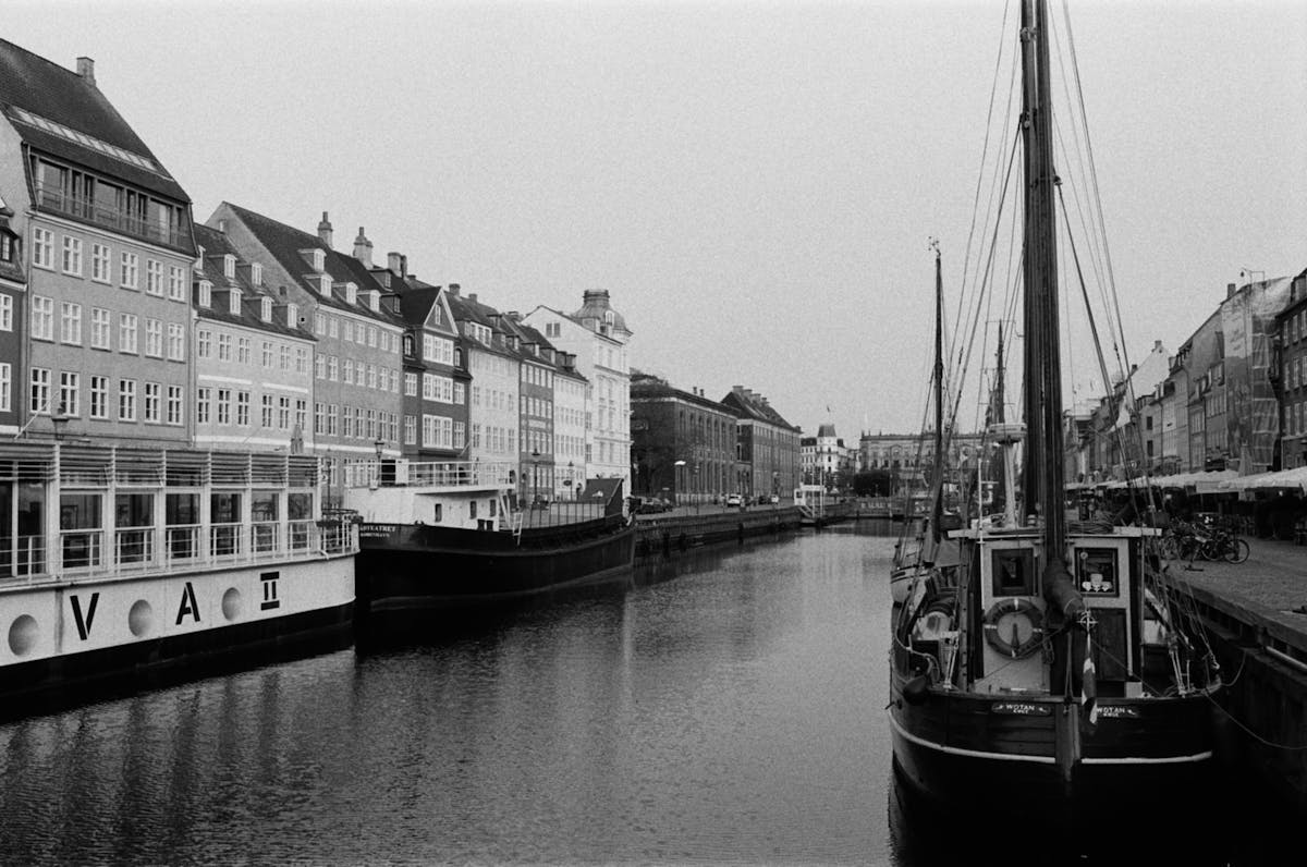Les meilleures façons de voyager à Copenhague Monochrome photo of Copenhagen harbor with boats and classic architecture along the canal.