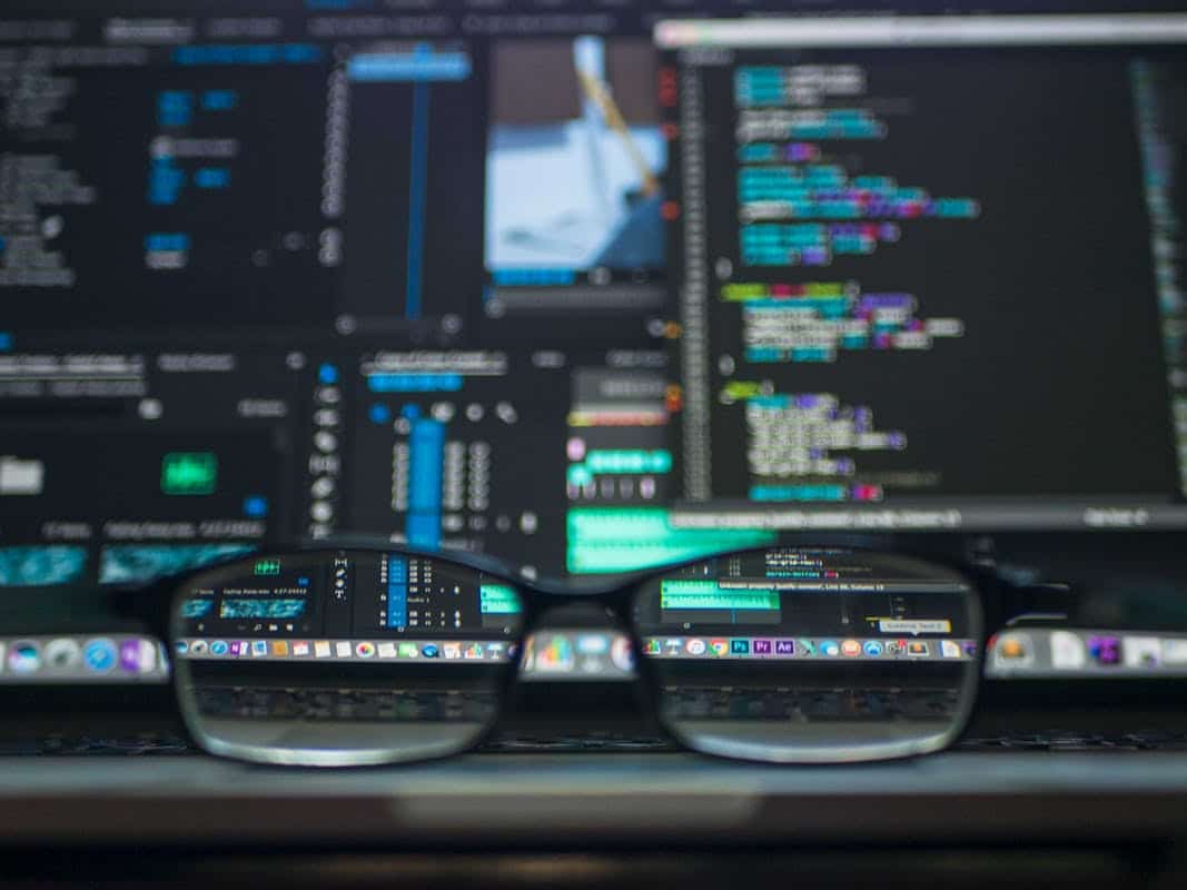 Explorer les sources gratuites et fiables pour accéder aux données automobiles Eyeglasses reflecting computer code on a monitor, ideal for technology and programming themes.