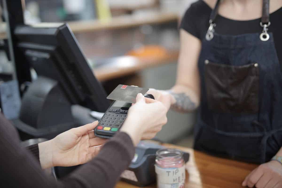 Qu’est-ce qui caractérise un mode de paiement « sans effort » en 2026 ? Close-up of customer and cashier during a credit card transaction at a store counter indoors.