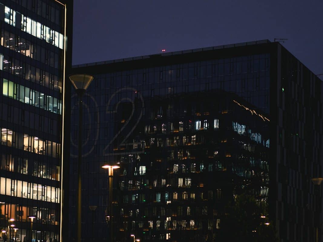 Économies virtuelles dans les jeux et les plateformes métaverses Modern office buildings at night with lit windows.